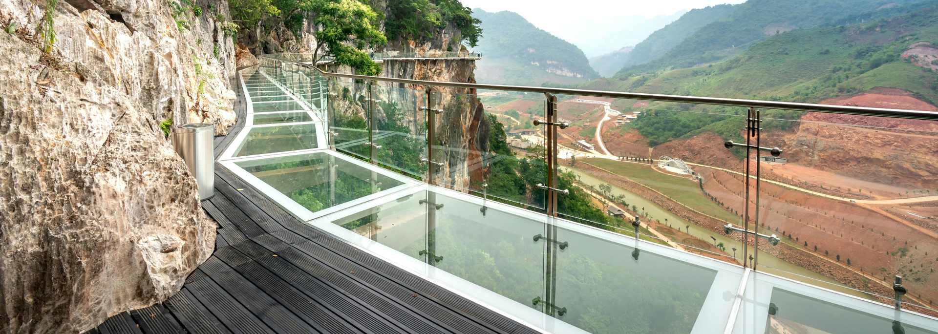 Glass walkway built along the side of a cliff with a view of a valley.