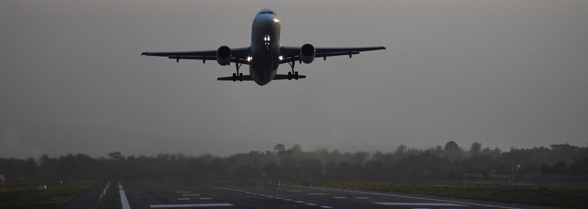 Airplane taking off from a runway on an overcast day.