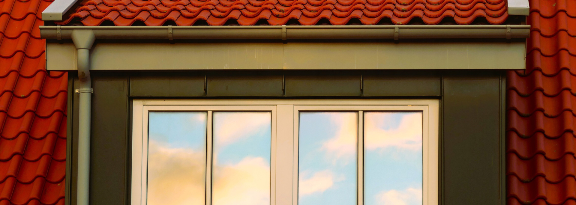 Picture of a tiled roof with a window underneath it. 