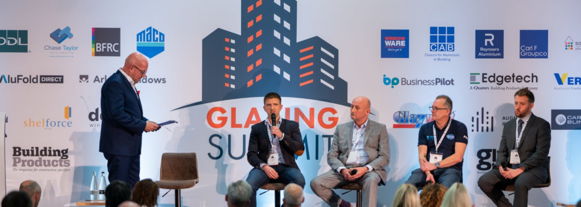 Panel of people at the Glazing Summit event; panelists are seated and speaking.