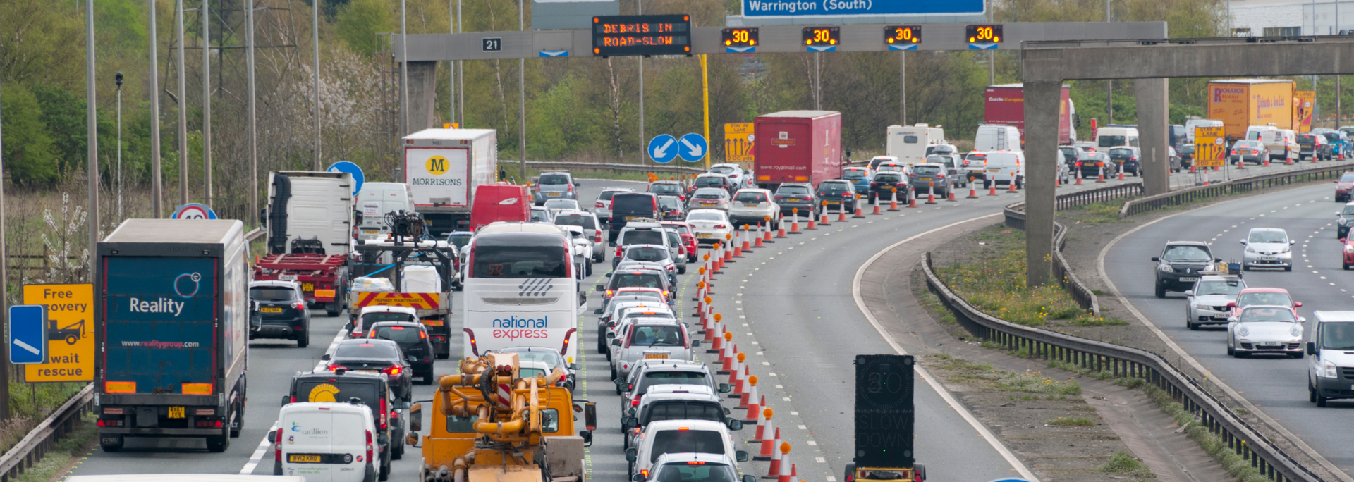 Traffic congestion on a multi-lane highway, lane closures indicated with orange cones.