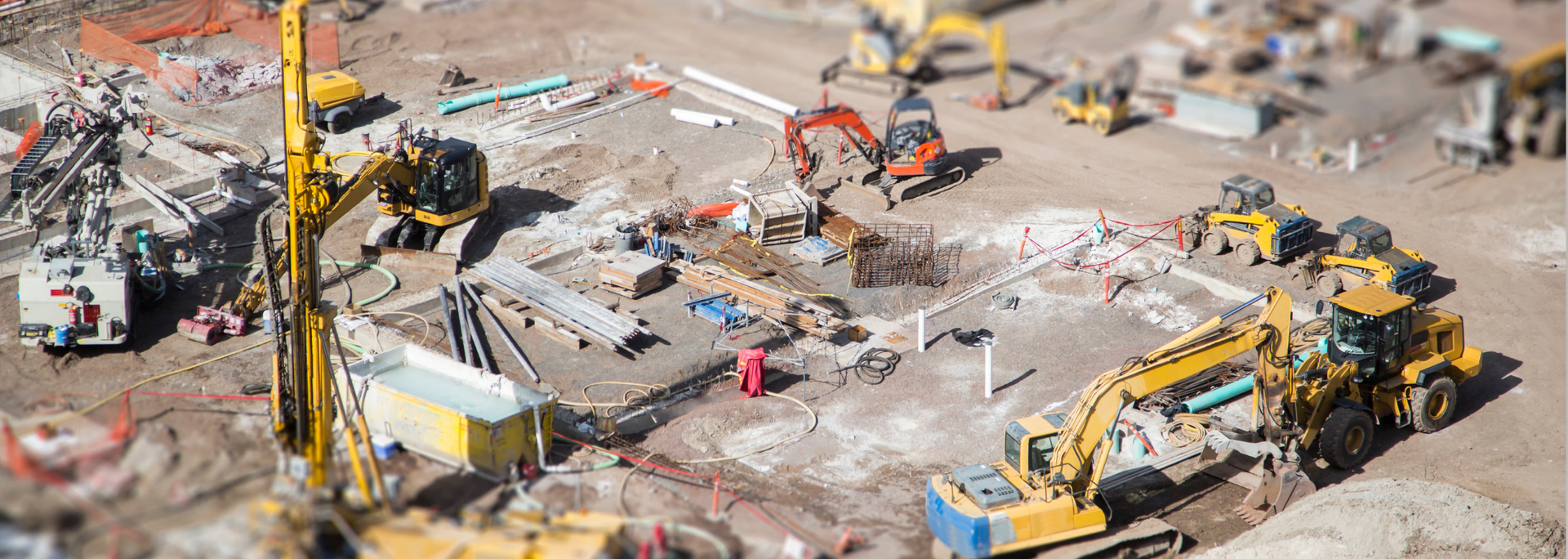Construction site with multiple yellow excavators and machinery.