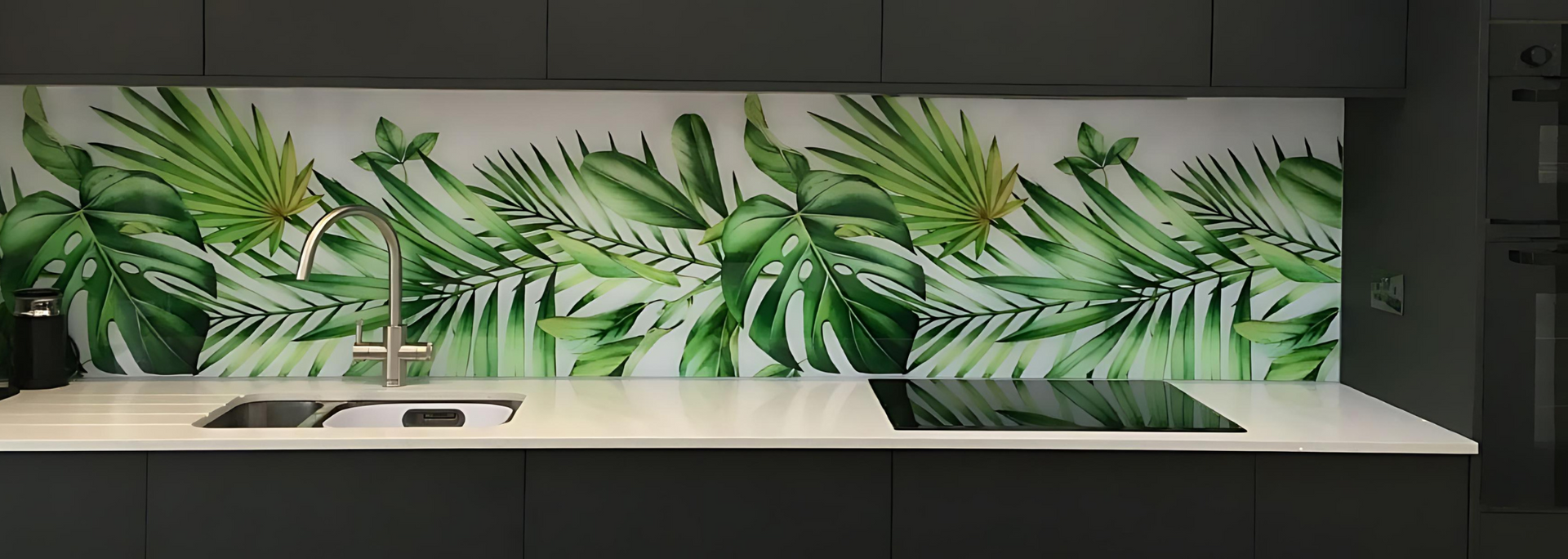 Kitchen with white countertop, dark gray cabinets, and a tropical leaf-patterned backsplash.