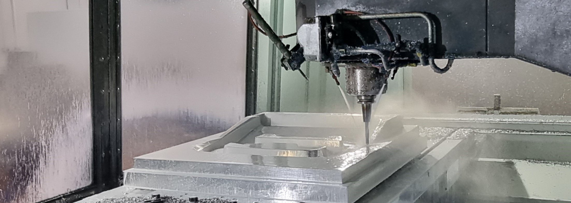 A CNC machine cutting a rectangular block, spraying coolant.