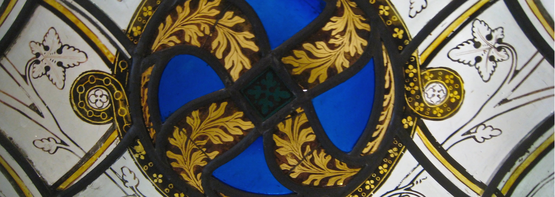 Stained glass window with blue and gold quatrefoil pattern and white floral accents.