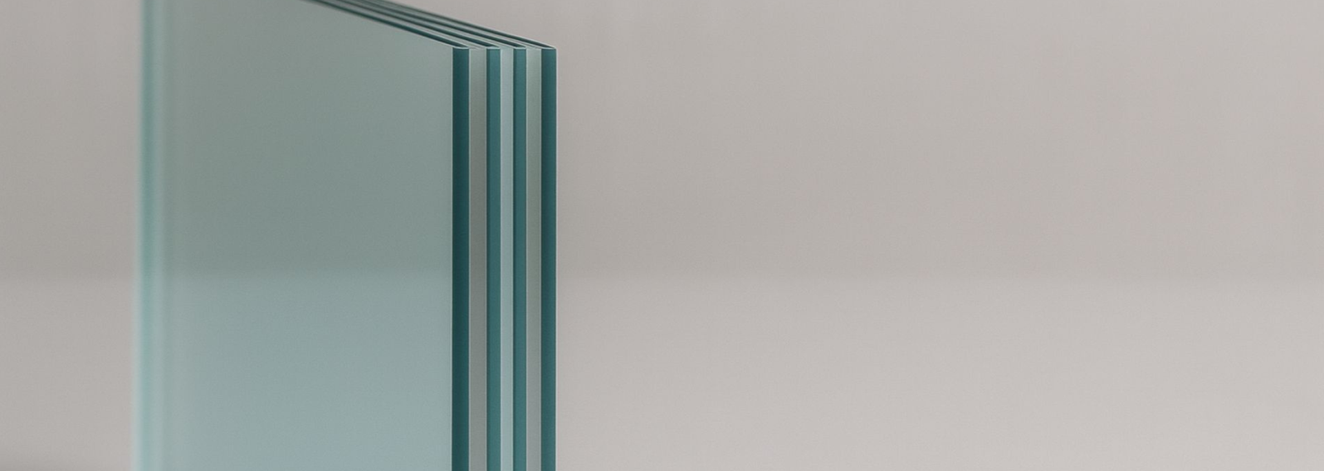 Stack of clear glass sheets against a light gray background.