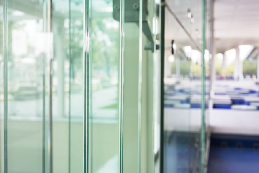 Glass panels, blurred interior with white and blue seating and exterior view.