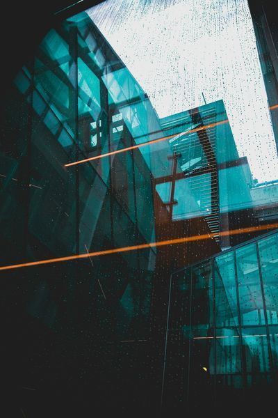 Glass building interior with teal and orange accents, dark atmosphere.