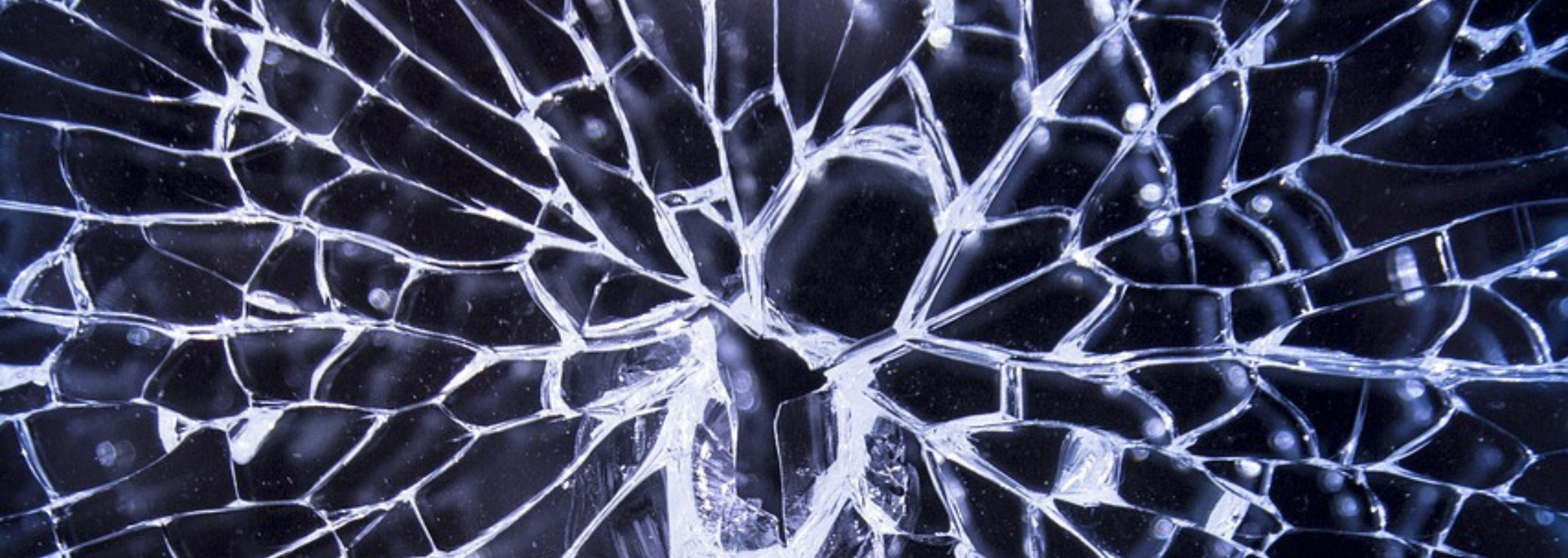 Cracked glass with a web of lines, shards, and dark shadows.