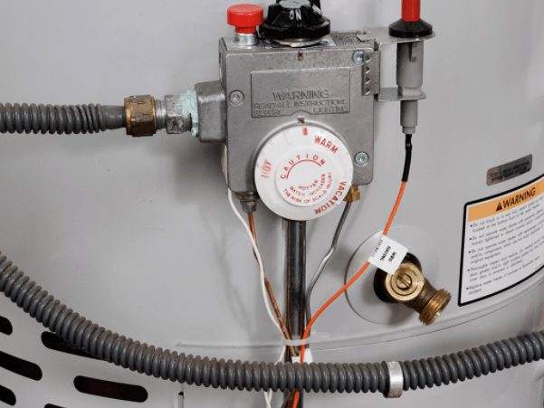 A close up of a gas water heater with a hose attached to it.