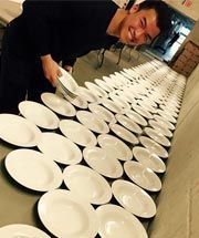 A man is standing in front of a table filled with plates.