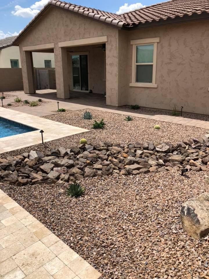 Backyard with pool, gravel landscaping, and tan house with patio.