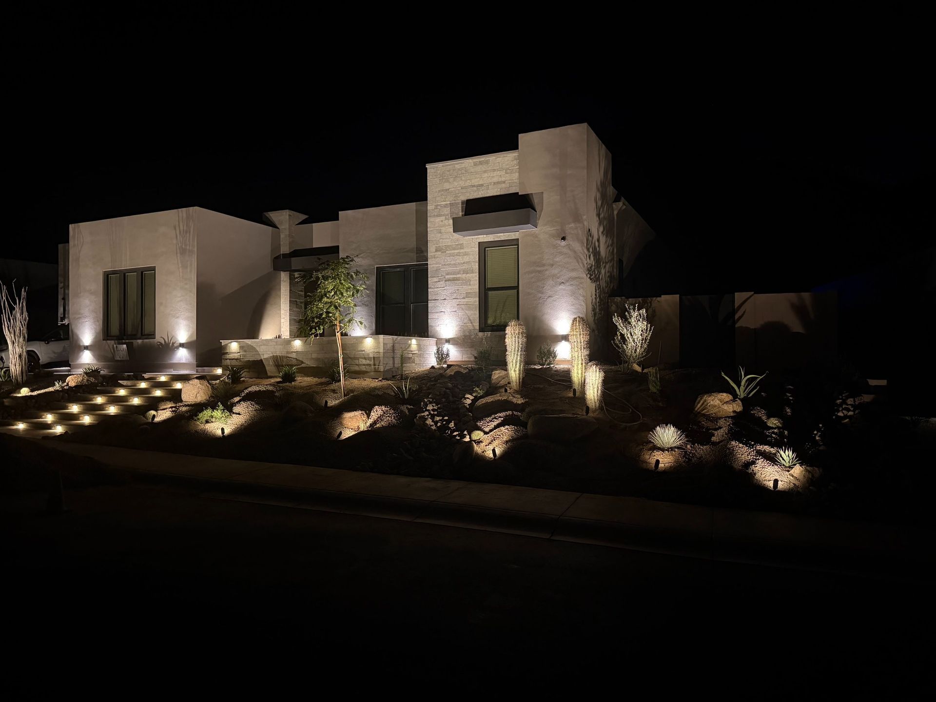 Modern house at night with warm exterior lighting and landscaped garden
