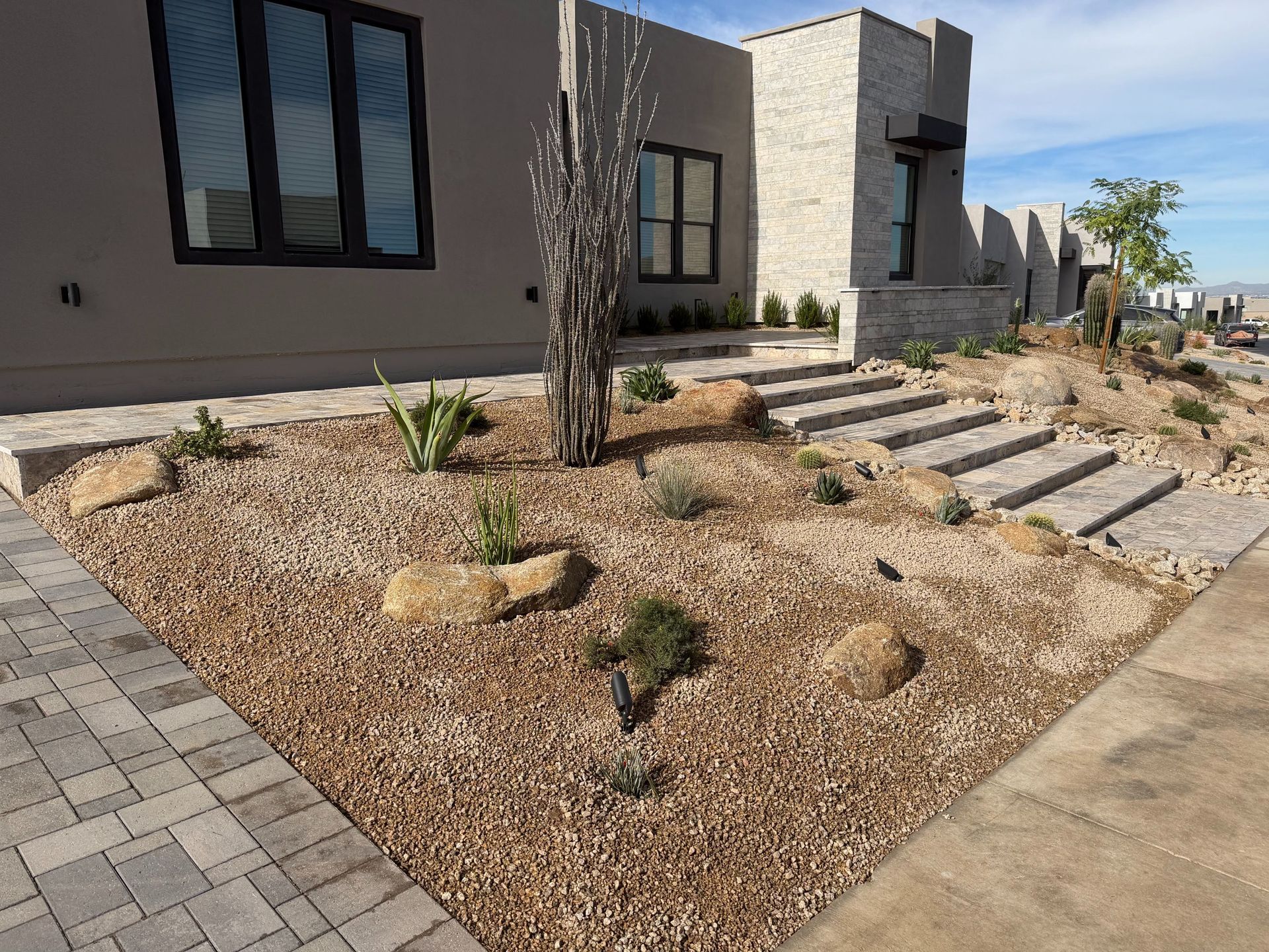 Modern house front yard with gravel landscaping, stepping stones, and small desert plants