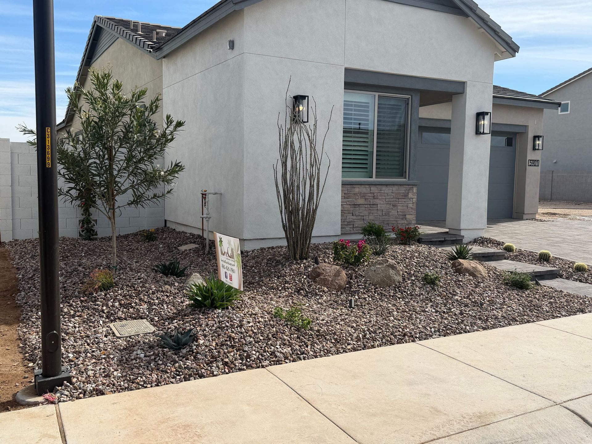 Modern single-story house with gravel landscaping, small shrubs, and a concrete sidewalk in front