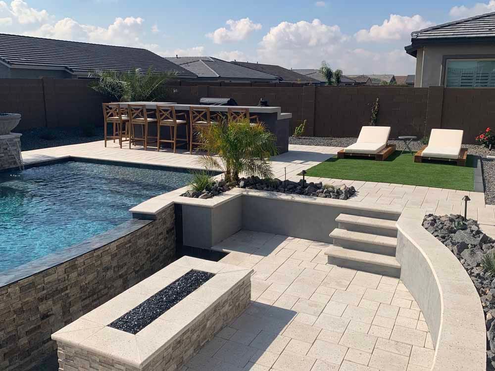 Backyard with pool, bar, and lounge chairs on a sunny day.