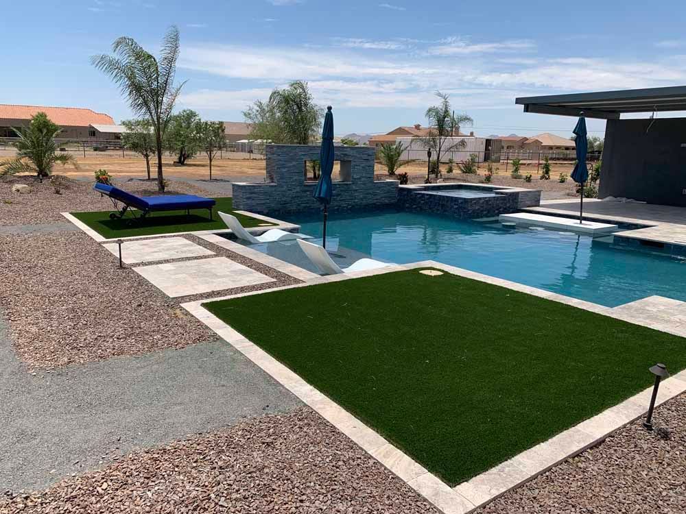 Poolside oasis with a pool, hot tub, and lounge chairs surrounded by landscaping.