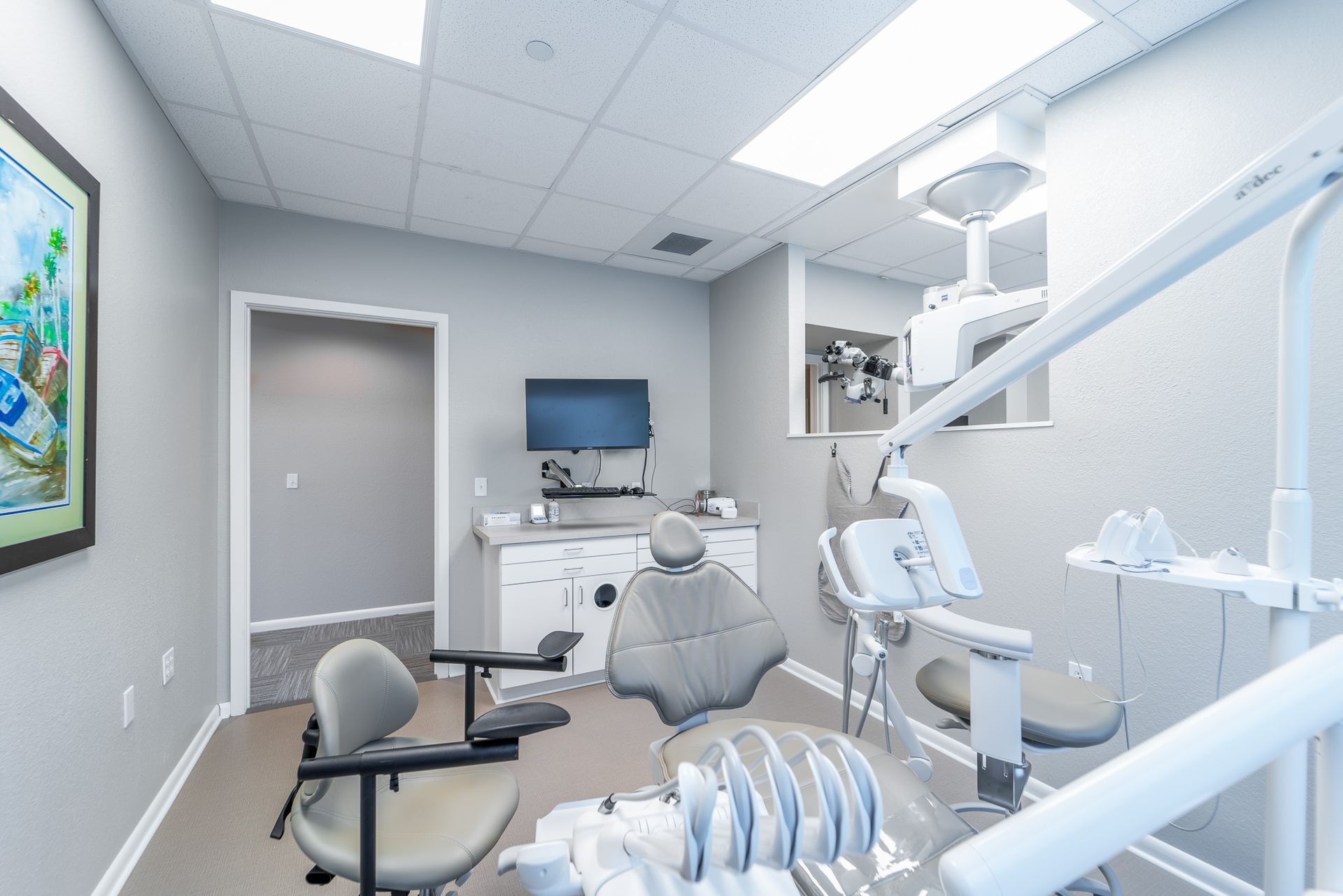 A dental office with a dental chair and a television on the wall.