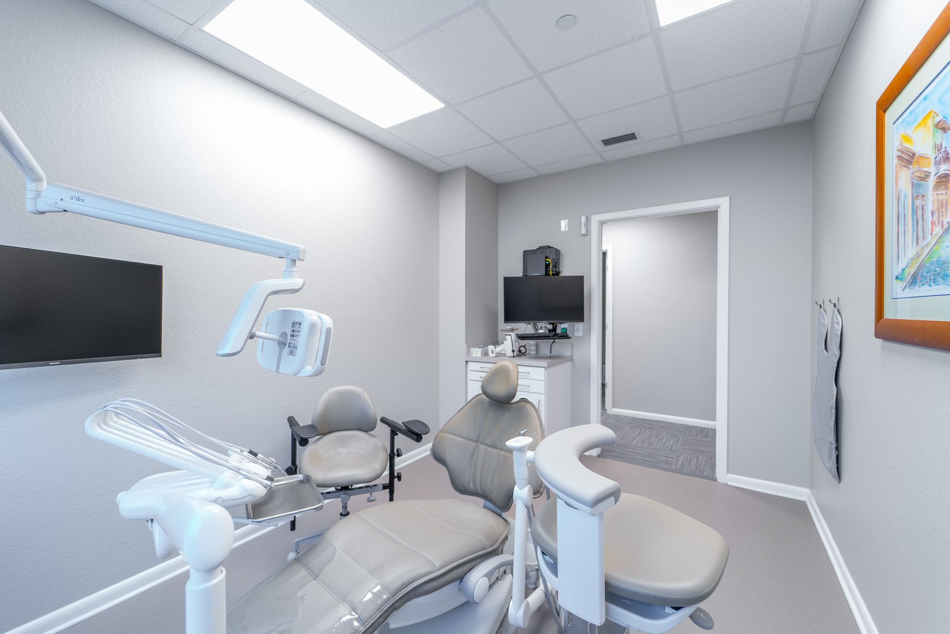 A dental office with a dental chair and a monitor.