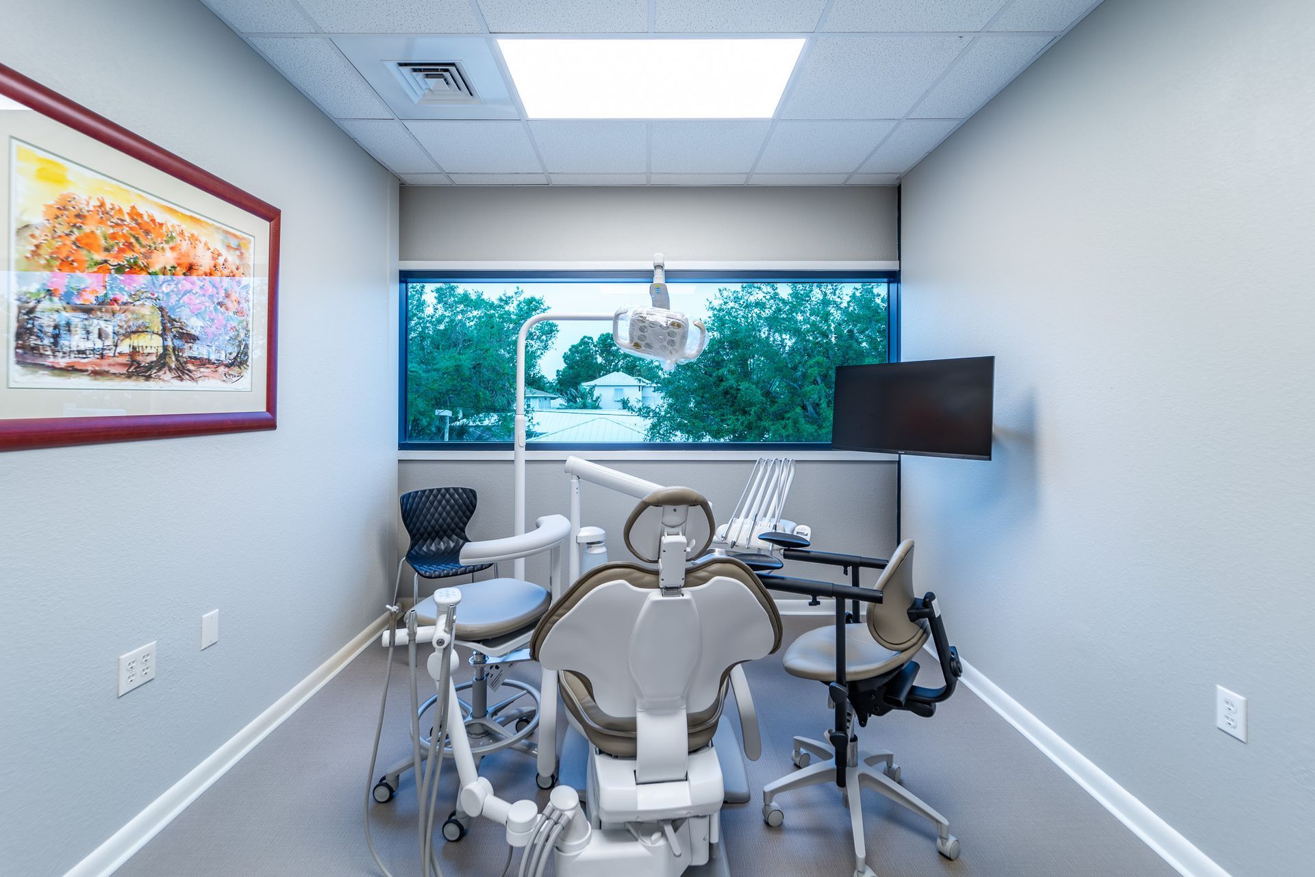 A dental office with a dental chair and a television on the wall.