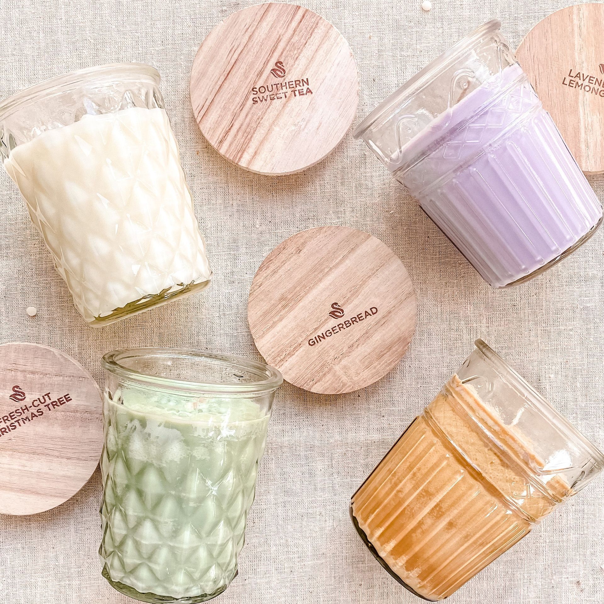 A group of candles with wooden lids are sitting on a table.