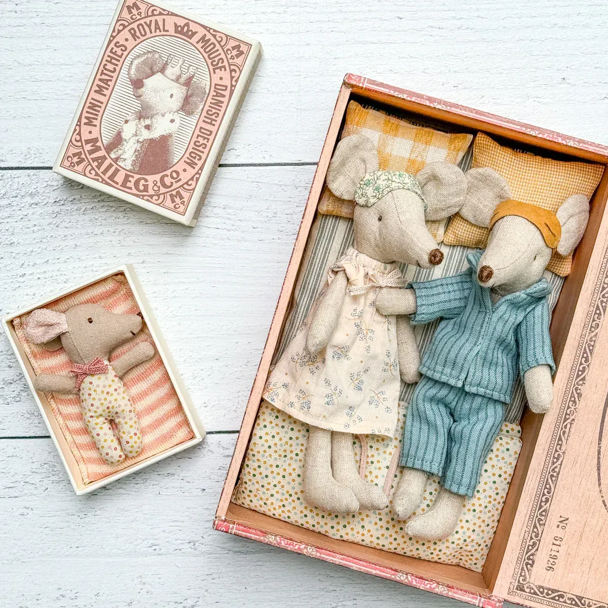 A couple of stuffed mice sitting on top of a bed in a box.