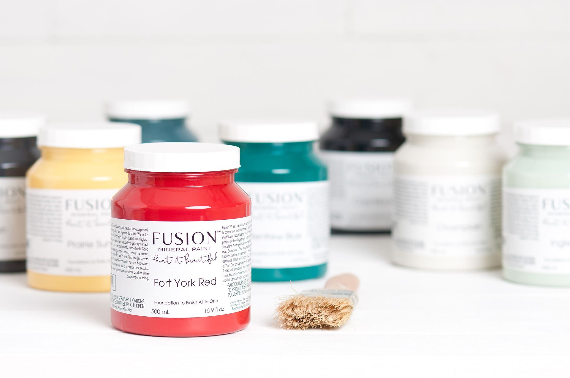 A bottle of fusion paint is sitting on a table next to a brush.