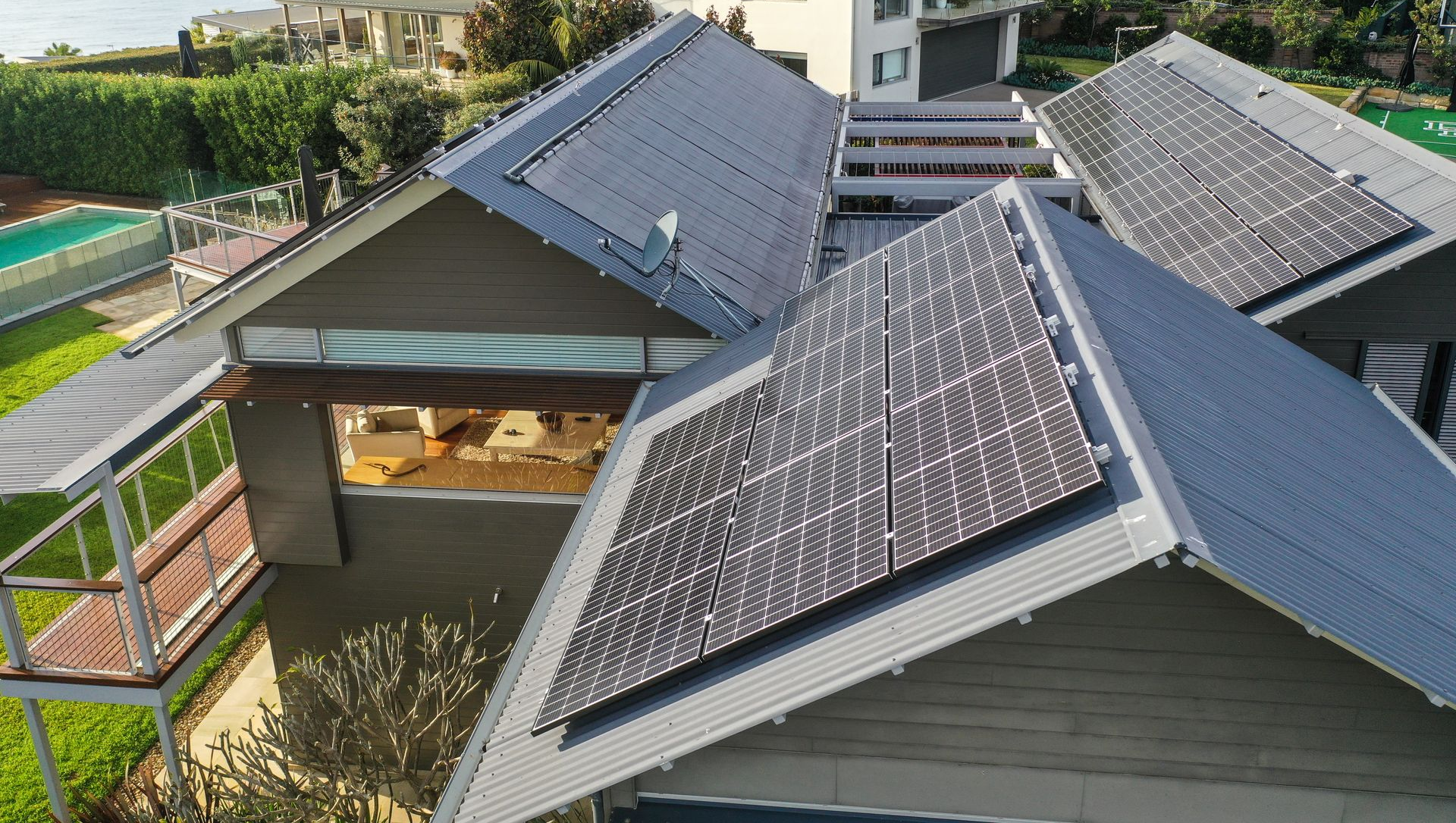 Rooftops with solar panels on a house, viewed from above in bright daylight.
