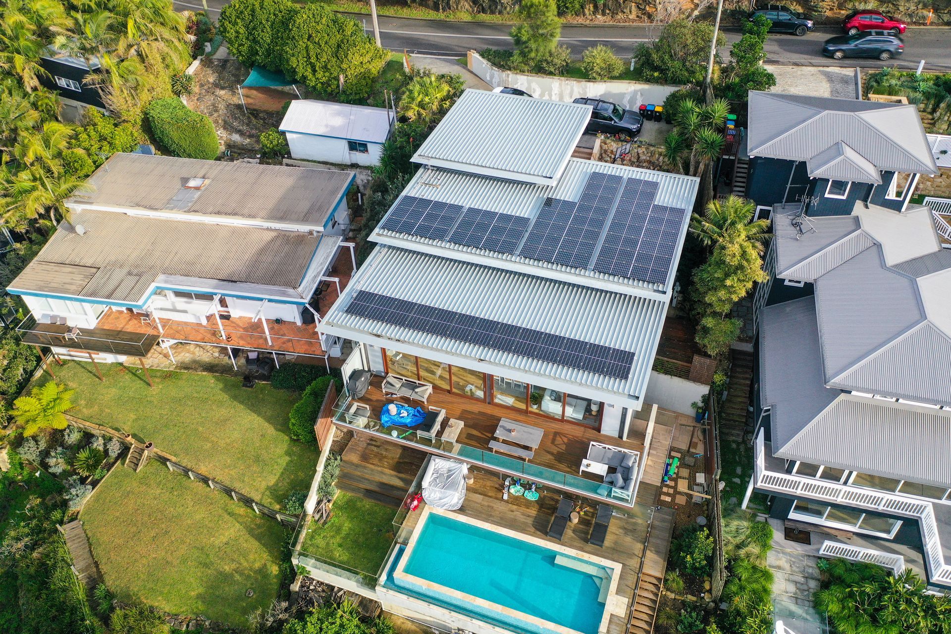 Aerial view of a house with solar panels and a backyard pool in a suburban neighborhood