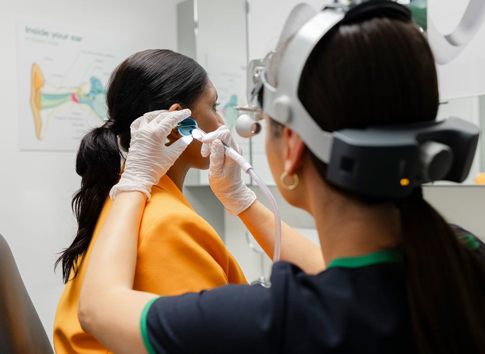 Audiologist examining a patient's ear canal with an otoscope to check for ear wax before a hearing test