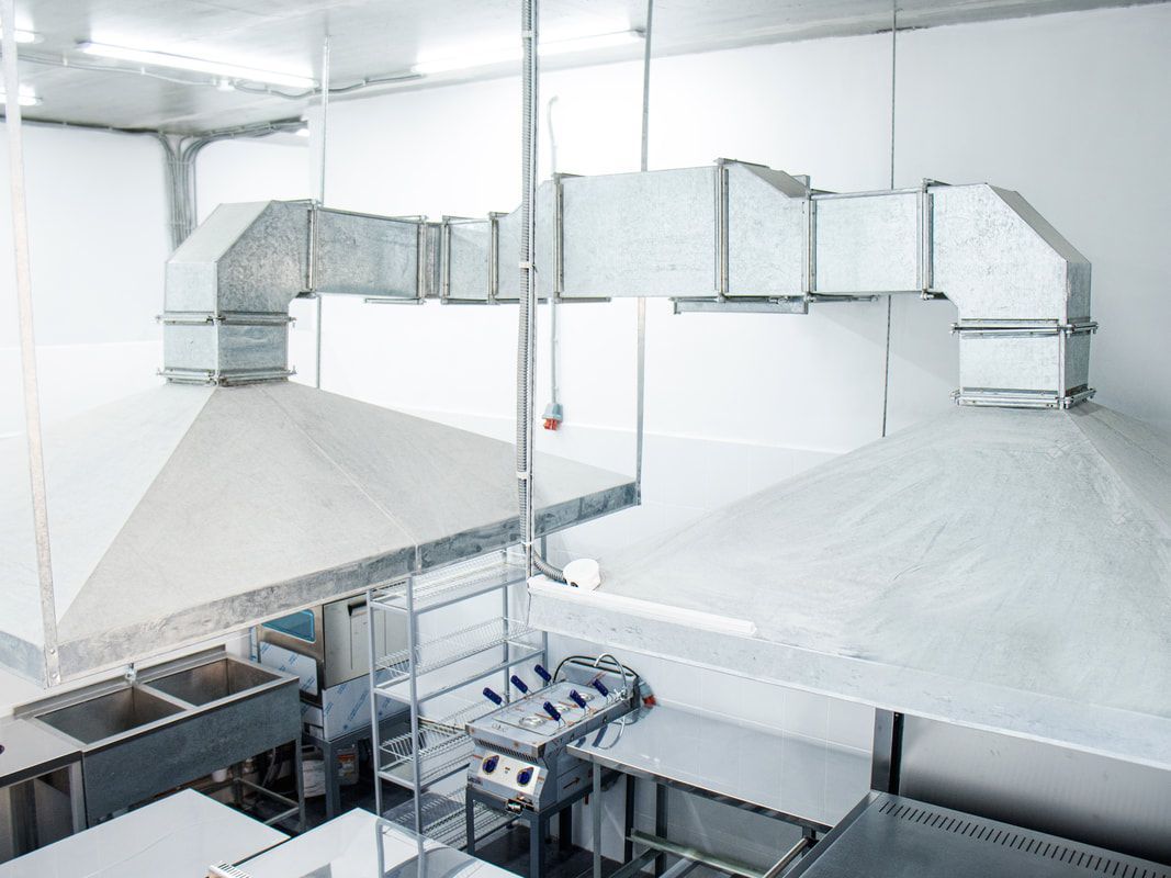Stainless steel kitchen exhaust hoods, fire suppression system and ductwork in a commercial kitchen.
