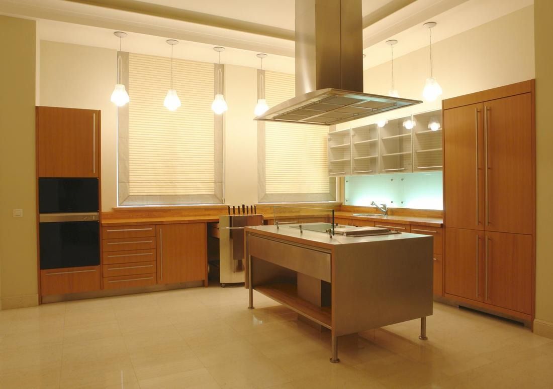 Modern kitchen with stainless steel island, wooden cabinets, and recessed lighting.