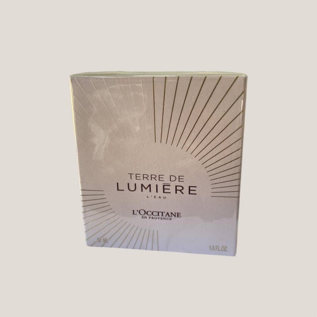 Caja de perfume L'Occitane Terre de Lumière con diseño de rayos de sol sobre fondo beige.