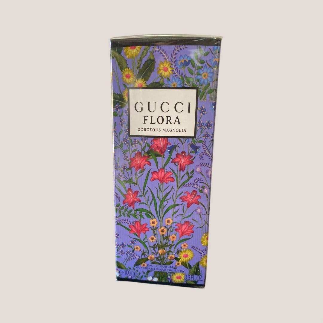 Caja de perfume floral Gucci Flora en color morado con flores rosas y hojas verdes.