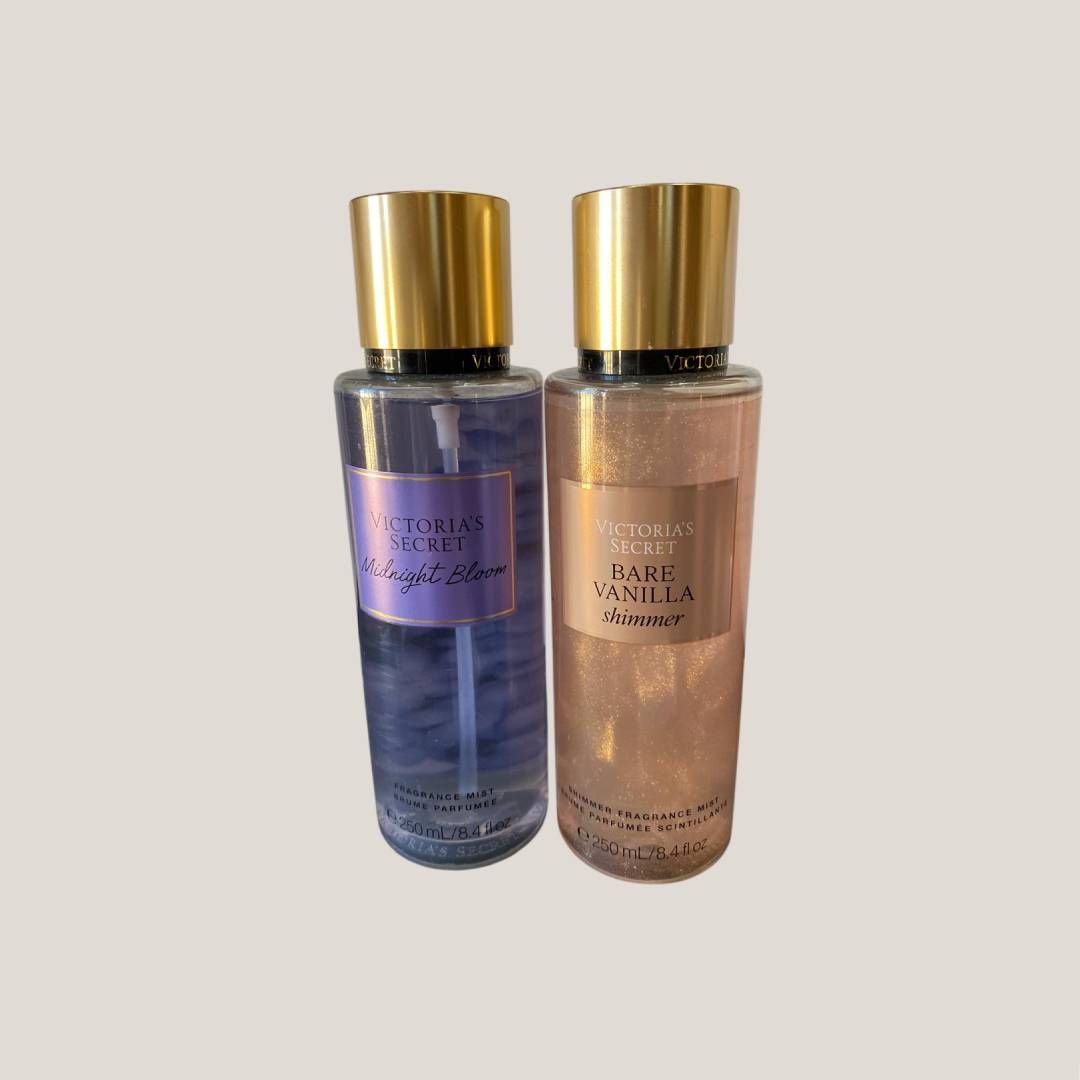 Dos frascos de perfume con tapones dorados, uno azul y otro rosa, colocados uno al lado del otro sobre una superficie clara.