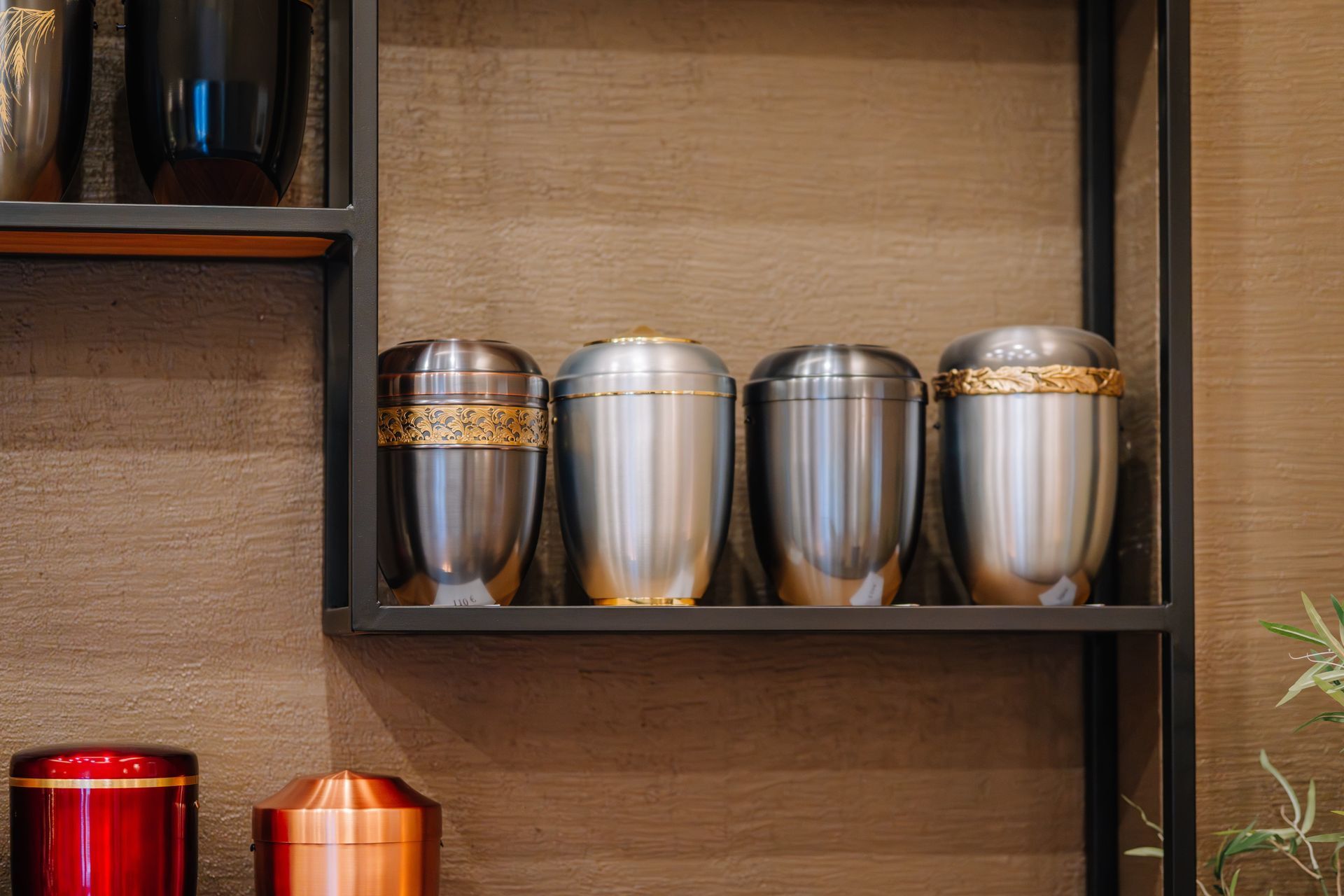 Decorative metal urns with gold bands displayed on wooden shelves