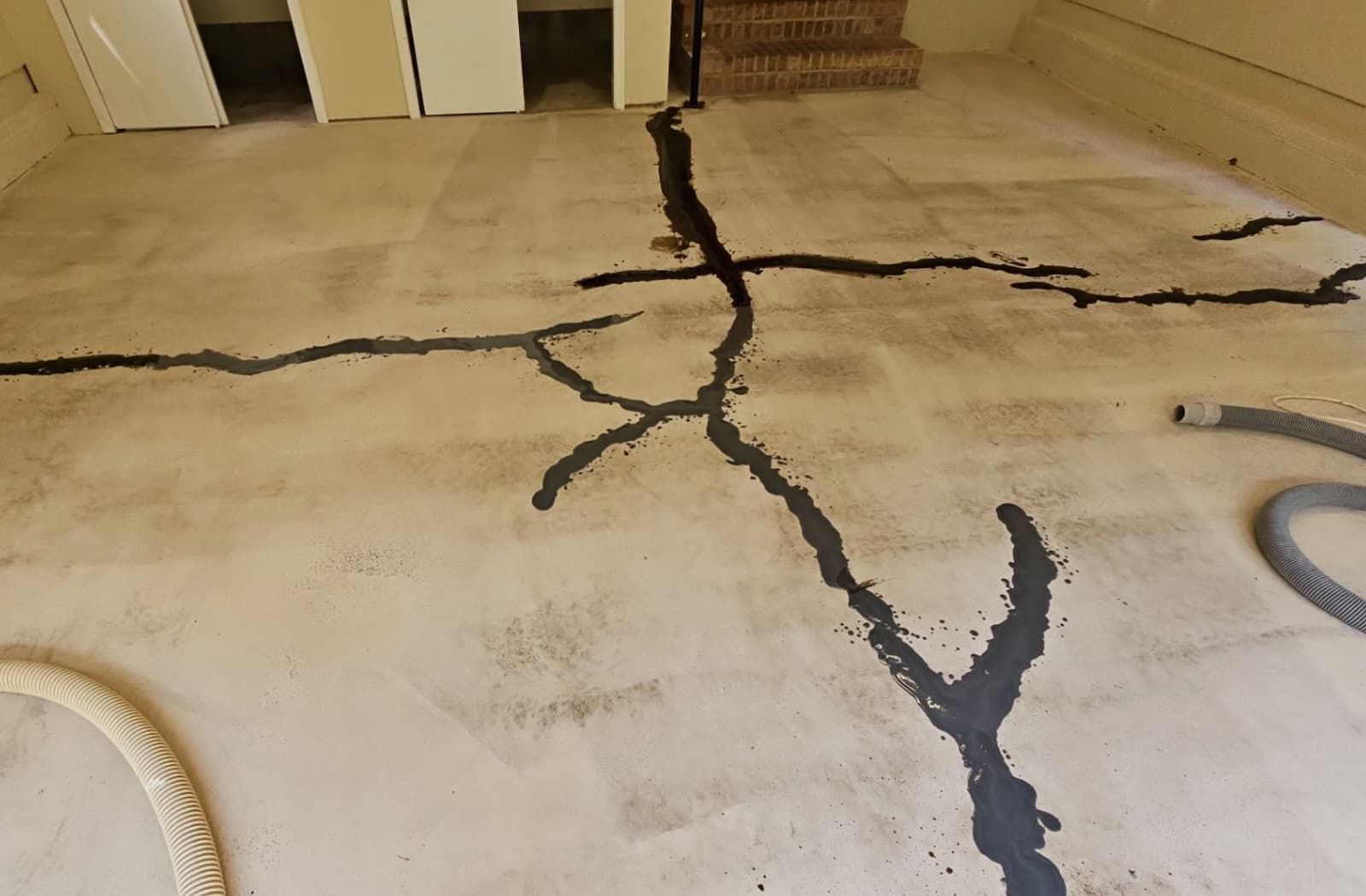 Basement concrete floor with deep branching cracks needing repair before any coating is applied