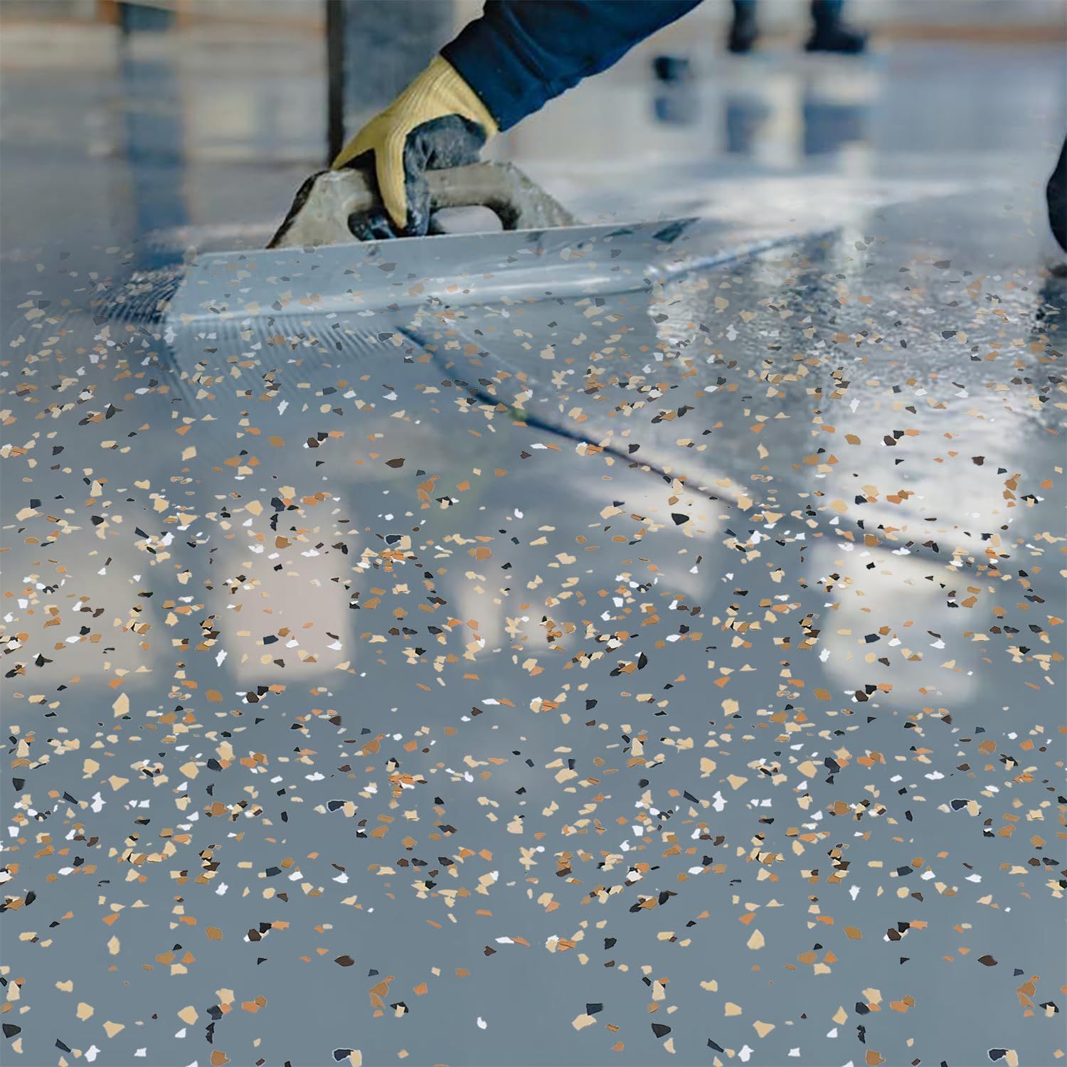 Contractor applying epoxy with colorful decorative flakes across a garage floor surface