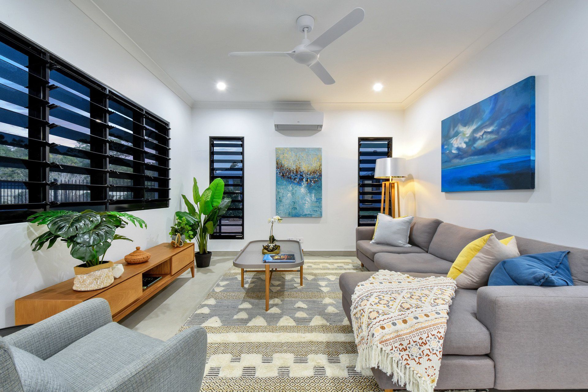 A living room with a couch and chairs and a ceiling fan
