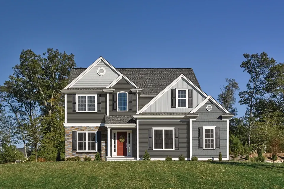 Two-story gray house with white trim and red front door on a sunny lawn