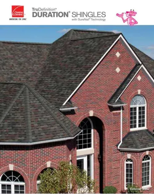 House with brick facade and dark asphalt shingle roof under a blue sky.