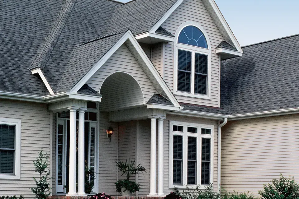 Front view of a gray suburban house with white trim and arched entryway