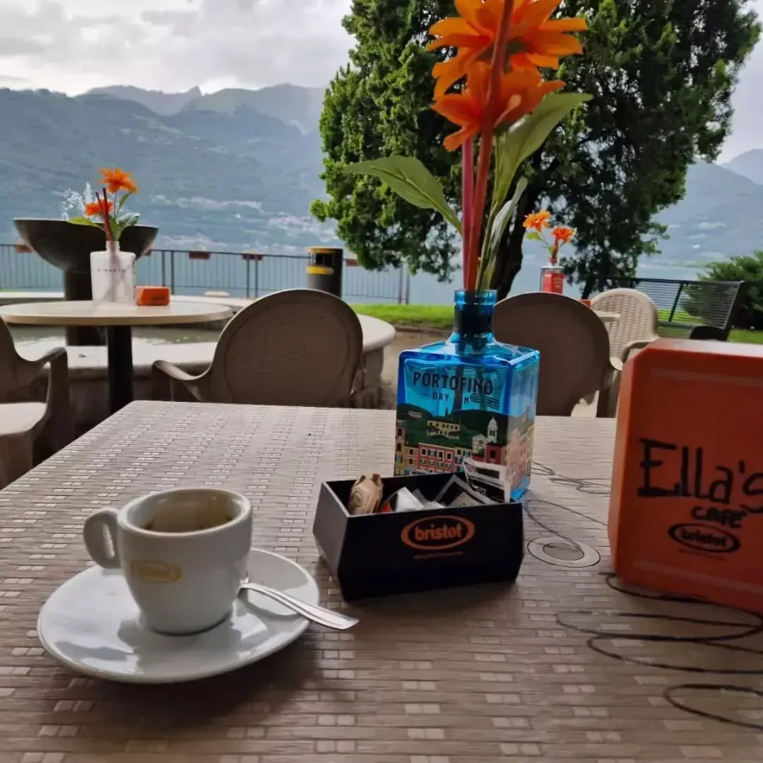 Tazzina da caffè espresso su un tavolo all'Ella's Cafe con fiori, zucchero e vista sul lago, con vista sulle montagne.
