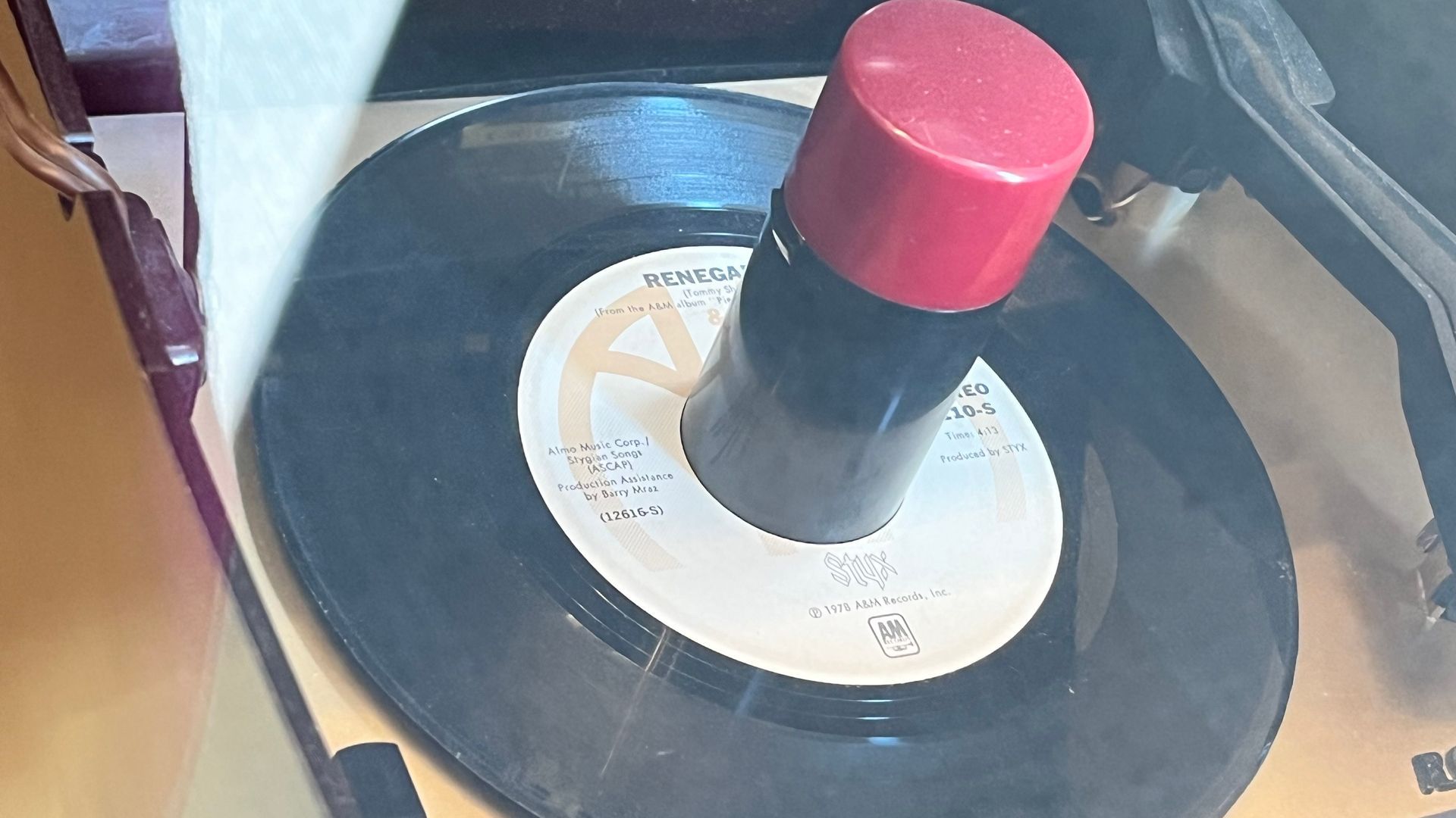 Vinyl record with a black spindle cap and red knob on a turntable player
