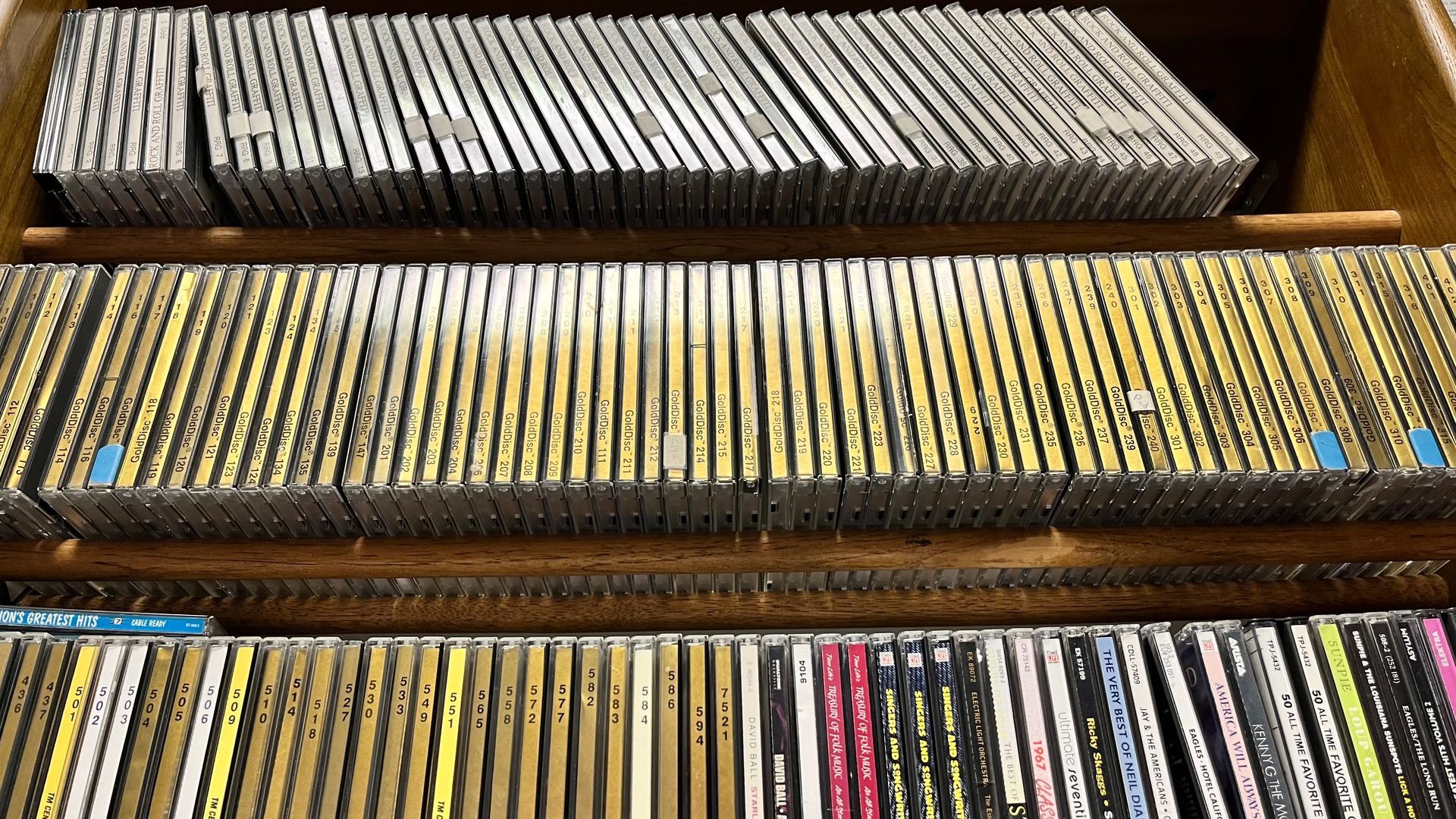 Wooden shelves filled with rows of CDs and DVDs in assorted colored cases
