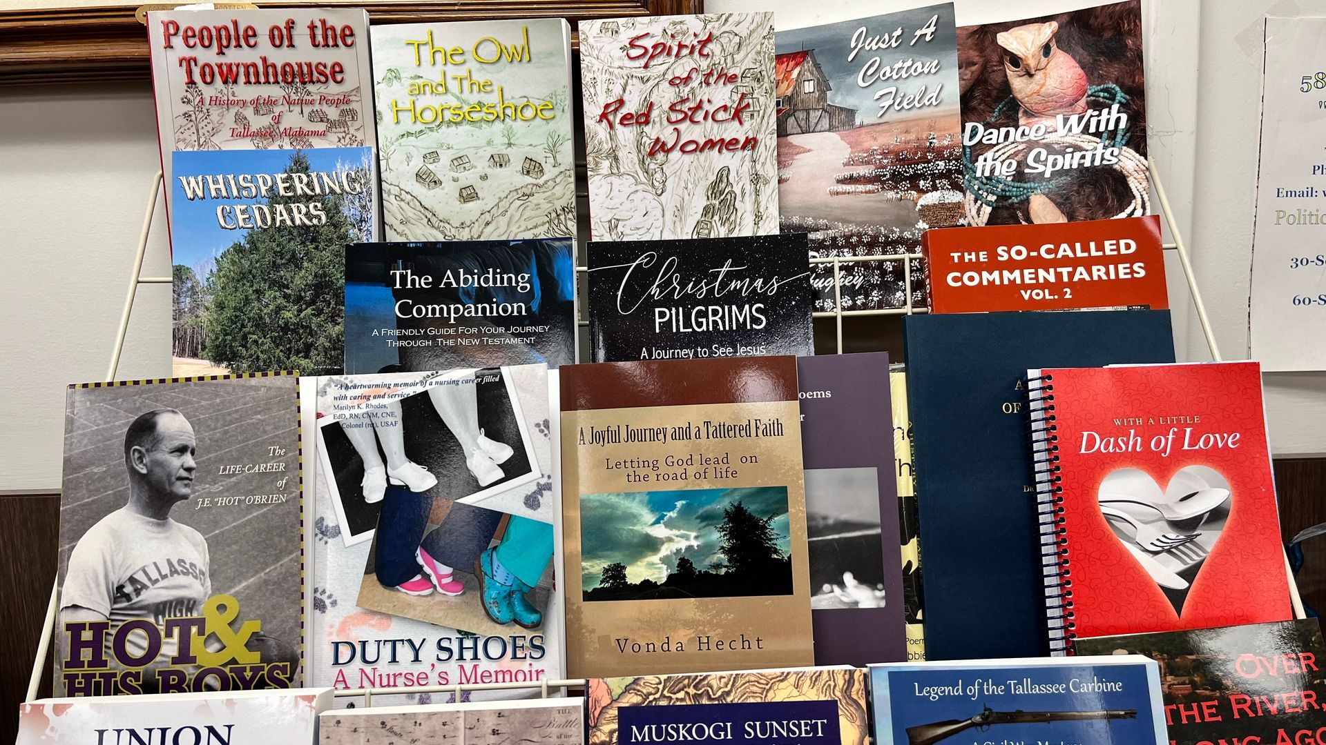 Books displayed in a library rack, including novels and nonfiction titles in colorful covers.
