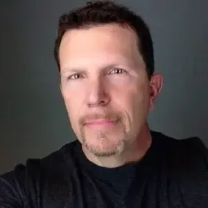 Man with short brown hair and goatee, wearing a black shirt, looking at the camera.