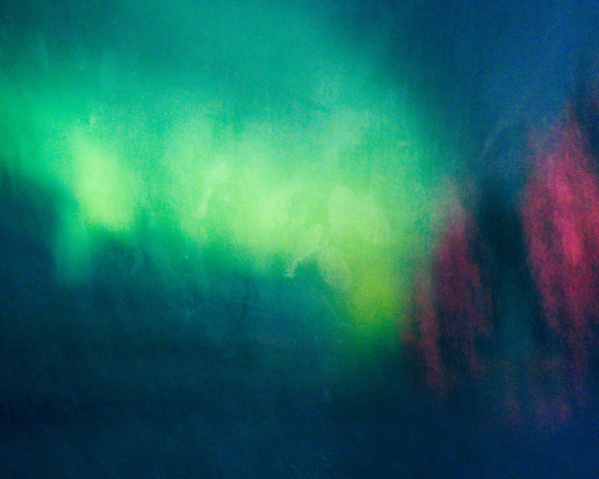 Abstract green and pink light against a dark blue background