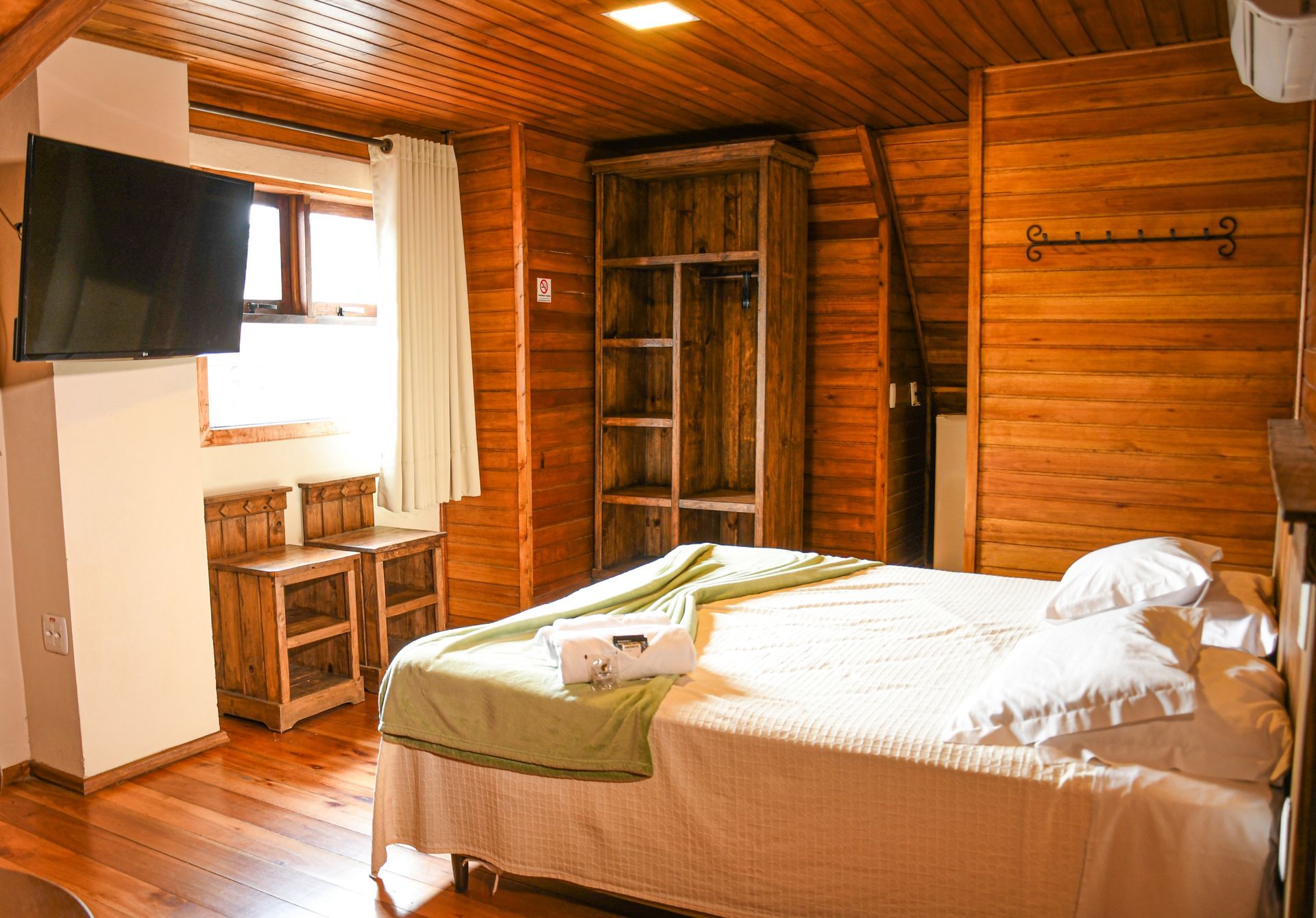 Quarto luminoso com duas camas, portas para varanda, TV de parede e decoração em tons neutros suaves.