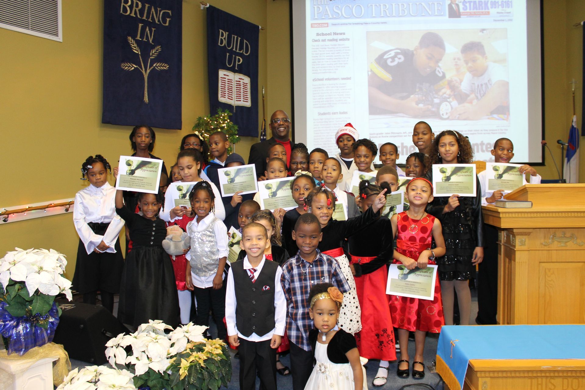 Children holding certificates on a church stage during a group ceremony